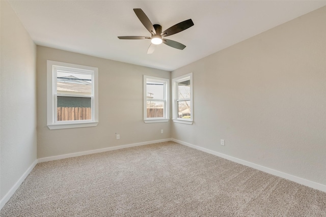 carpeted empty room featuring baseboards and ceiling fan