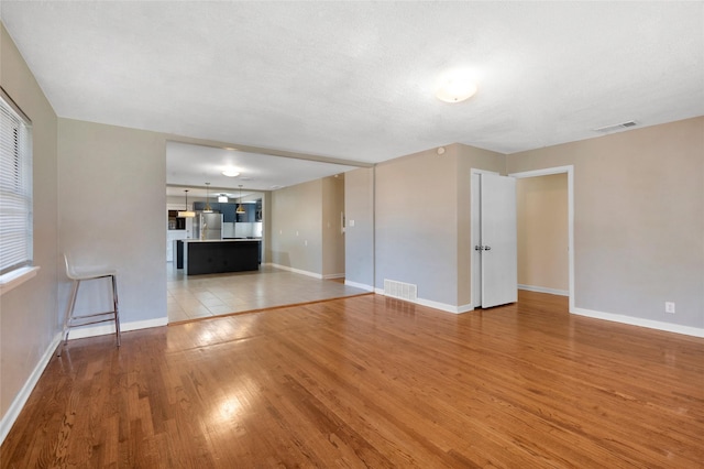 4021 Kenley St, Fort Worth, TX 76107 - unfurnished living room with visible vents, baseboards, and light wood-style flooring