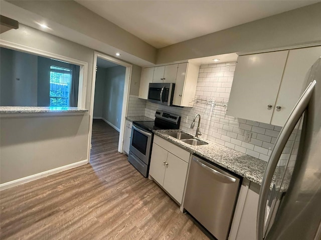 5049 Cedar Springs Rd Unit 120, Dallas, TX 75235 - kitchen featuring appliances with stainless steel finishes, a sink, white cabinets, decorative backsplash, and wood finished floors