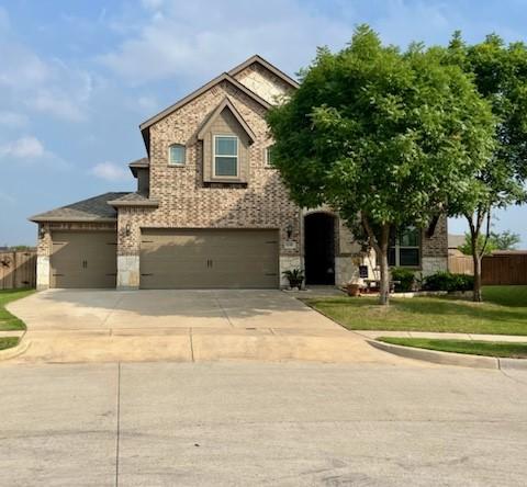 traditional-style house featuring concrete driveway, a front lawn, fence, and brick siding