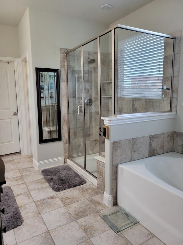 bathroom with a bath, baseboards, and a stall shower