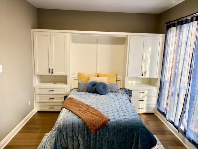 bedroom with multiple windows, dark wood-type flooring, and baseboards