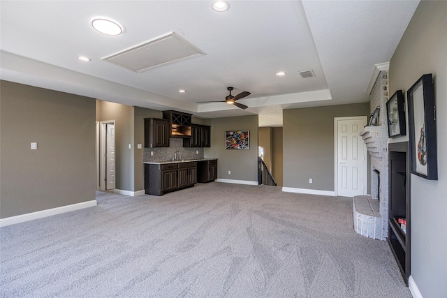 unfurnished living room featuring a tray ceiling, baseboards, light colored carpet, attic access, and recessed lighting