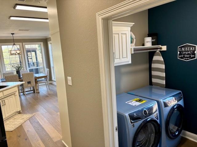 laundry area featuring independent washer and dryer, crown molding, a chandelier, light wood-style floors, and baseboards