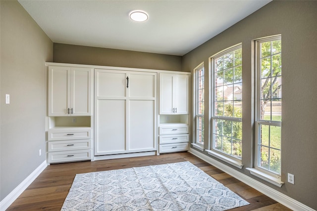 bedroom with baseboards, multiple windows, and dark wood-style flooring