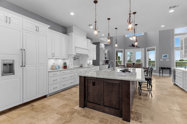 639 Calm Water Cv, Princeton, TX 75407 - kitchen featuring white cabinetry, stone tile floors, a breakfast bar, a large island, and visible vents