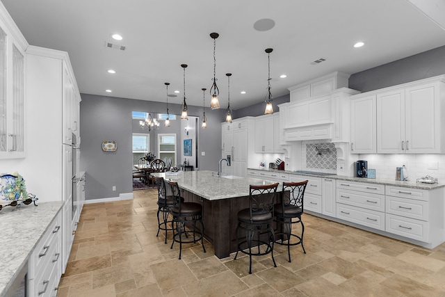 639 Calm Water Cv, Princeton, TX 75407 - kitchen featuring a breakfast bar area, a sink, tasteful backsplash, and stone tile floors