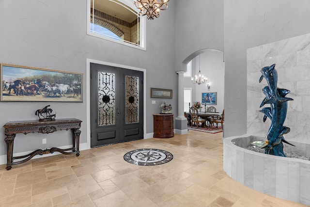 639 Calm Water Cv, Princeton, TX 75407 - foyer entrance featuring a chandelier, baseboards, arched walkways, a high ceiling, and stone tile floors