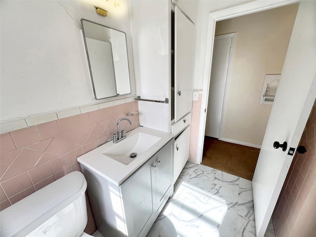 half bathroom with tile walls, vanity, and toilet