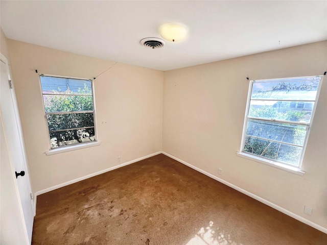 carpeted empty room with a wealth of natural light, visible vents, and baseboards