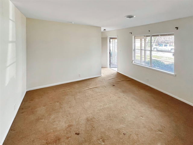 empty room with carpet, visible vents, and baseboards