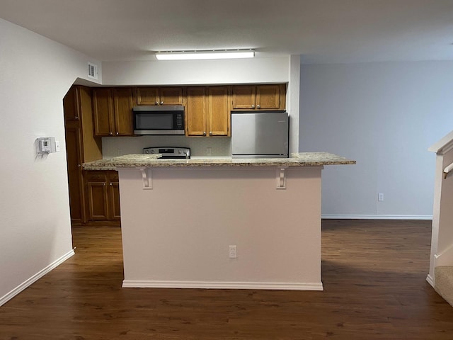 kitchen featuring dark wood-style floors, baseboards, visible vents, appliances with stainless steel finishes, and a center island