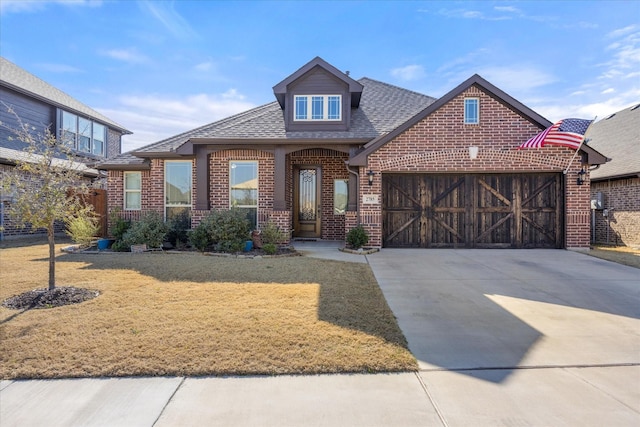 view of front of home with driveway, roof with shingles, a front lawn, a garage, and brick siding