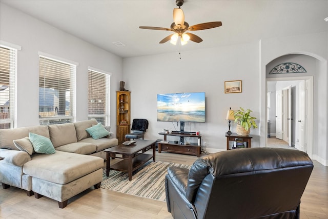 living room with visible vents, baseboards, arched walkways, ceiling fan, and light wood-style floors