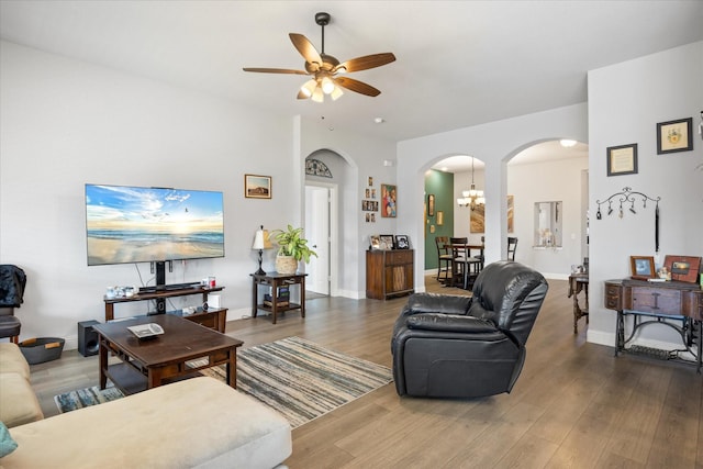 living room with arched walkways, ceiling fan with notable chandelier, baseboards, and wood finished floors