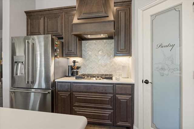 kitchen featuring light countertops, dark brown cabinets, premium range hood, and appliances with stainless steel finishes