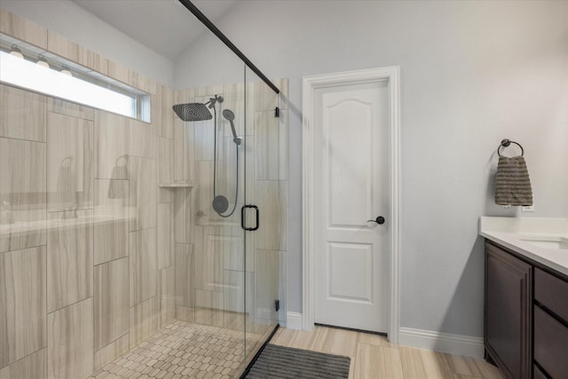 full bathroom with a shower stall, baseboards, lofted ceiling, wood finished floors, and vanity