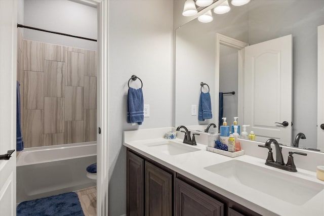 bathroom featuring double vanity, washtub / shower combination, and a sink