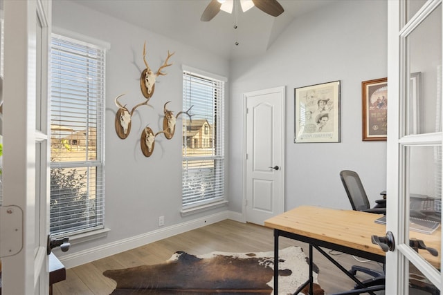 home office featuring baseboards, light wood-style floors, ceiling fan, and vaulted ceiling