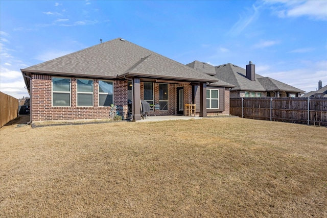 back of property with a yard, a fenced backyard, brick siding, and a shingled roof