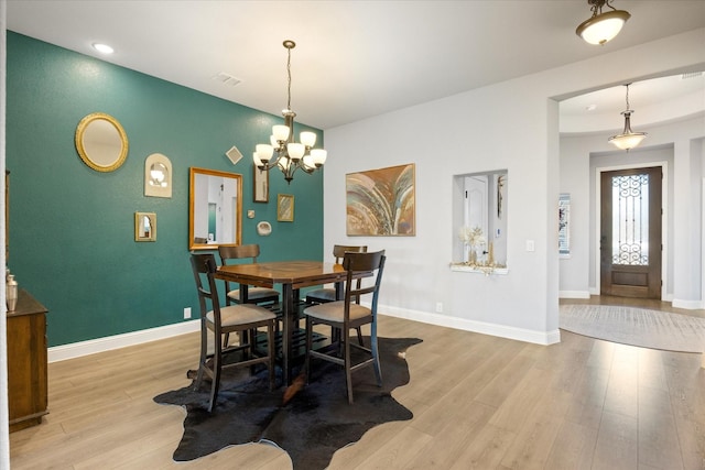 dining area featuring light wood finished floors, visible vents, a notable chandelier, and baseboards