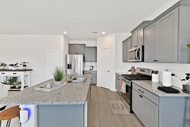 kitchen featuring a sink, stainless steel appliances, light wood-style flooring, and gray cabinets