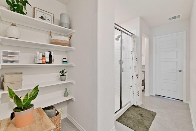 interior space featuring tile patterned flooring, visible vents, a stall shower, and baseboards