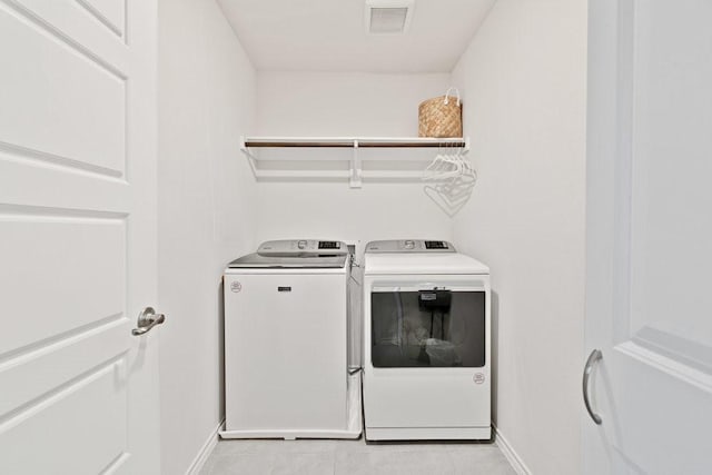 laundry room featuring visible vents, baseboards, washing machine and dryer, light tile patterned floors, and laundry area