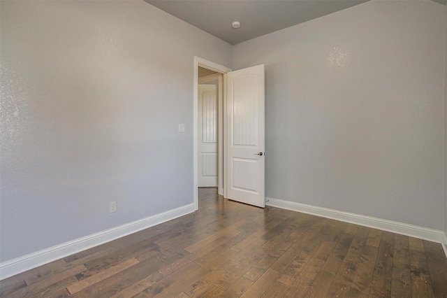 unfurnished room featuring baseboards and dark wood finished floors