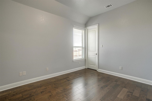 empty room with visible vents, baseboards, dark wood-style floors, and vaulted ceiling