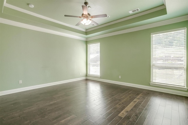 spare room featuring dark wood finished floors, visible vents, a raised ceiling, and ornamental molding