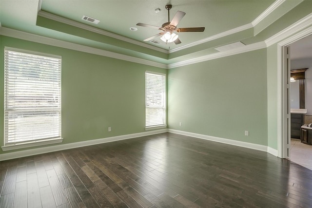 spare room with visible vents, ceiling fan, a tray ceiling, ornamental molding, and dark wood-style flooring