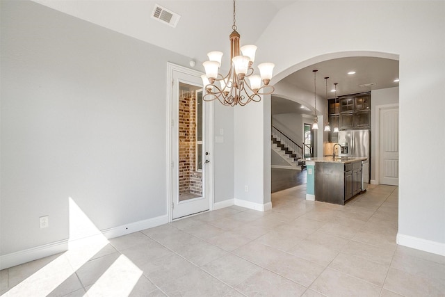 unfurnished dining area featuring visible vents, lofted ceiling, light tile patterned flooring, arched walkways, and a notable chandelier