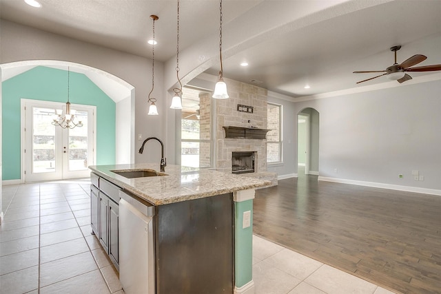 kitchen featuring ceiling fan with notable chandelier, a sink, stainless steel dishwasher, open floor plan, and light tile patterned floors