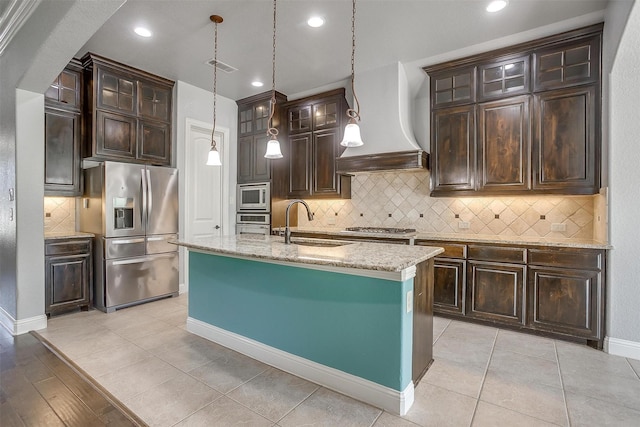 kitchen featuring a sink, dark brown cabinetry, custom range hood, appliances with stainless steel finishes, and pendant lighting