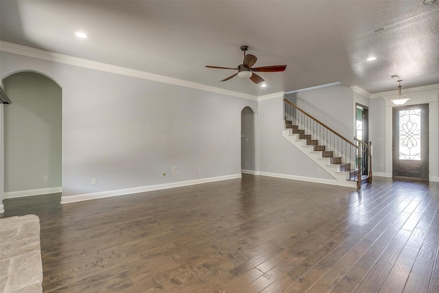 unfurnished living room with a ceiling fan, dark wood finished floors, stairway, arched walkways, and baseboards