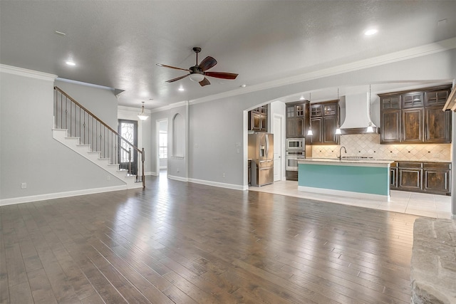 unfurnished living room featuring a ceiling fan, light wood-style floors, arched walkways, and baseboards