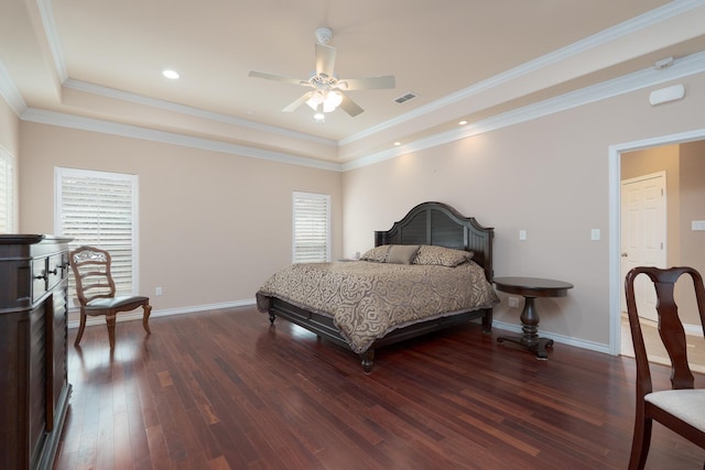 bedroom featuring visible vents, a tray ceiling, wood finished floors, crown molding, and baseboards