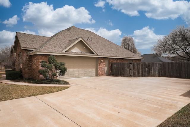 view of front facade with brick siding, a shingled roof, driveway, and fence