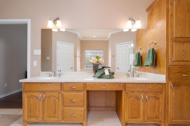 bathroom with double vanity, crown molding, baseboards, and a sink