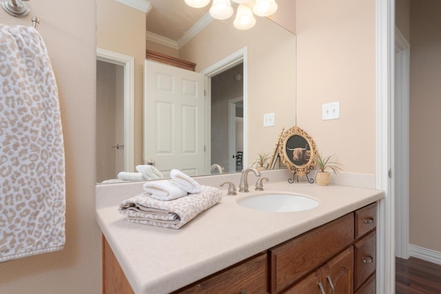 bathroom with baseboards, ornamental molding, an inviting chandelier, wood finished floors, and vanity