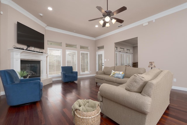 living room featuring a glass covered fireplace, ceiling fan, baseboards, and wood finished floors