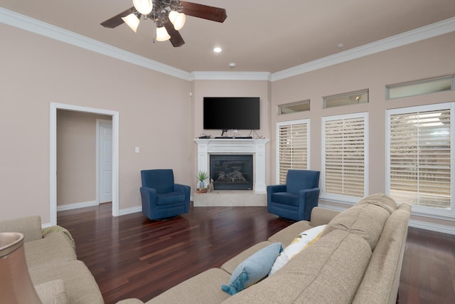 living area featuring baseboards, ornamental molding, wood finished floors, a glass covered fireplace, and a ceiling fan