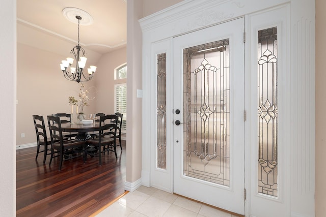 foyer featuring a chandelier, light wood-style flooring, baseboards, and lofted ceiling