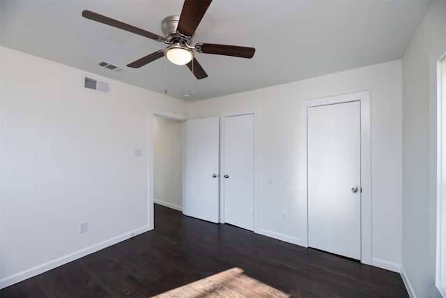 unfurnished bedroom featuring visible vents, baseboards, and dark wood-style flooring