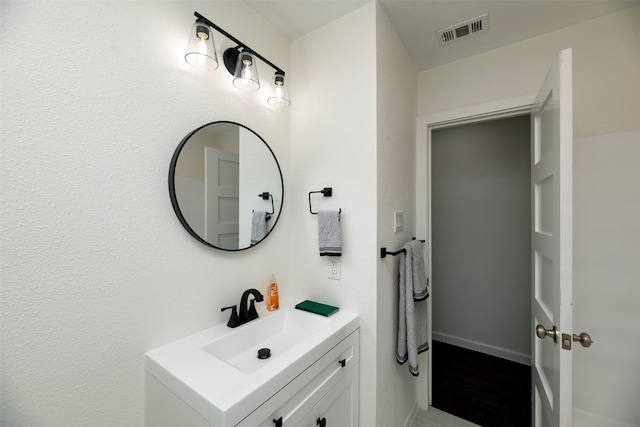 bathroom with vanity, wood finished floors, baseboards, and visible vents