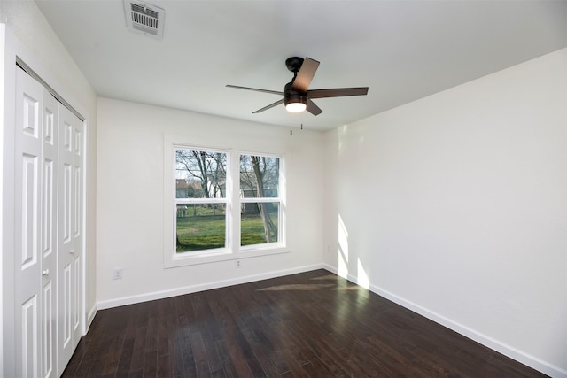 unfurnished bedroom with a closet, visible vents, dark wood-type flooring, and baseboards