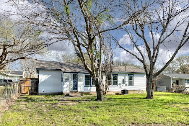 rear view of property with entry steps, a yard, and fence