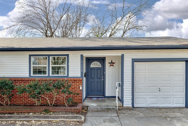 view of exterior entry featuring brick siding, concrete driveway, and a shingled roof