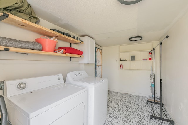 laundry area featuring baseboards, cabinet space, a textured ceiling, and washer and clothes dryer